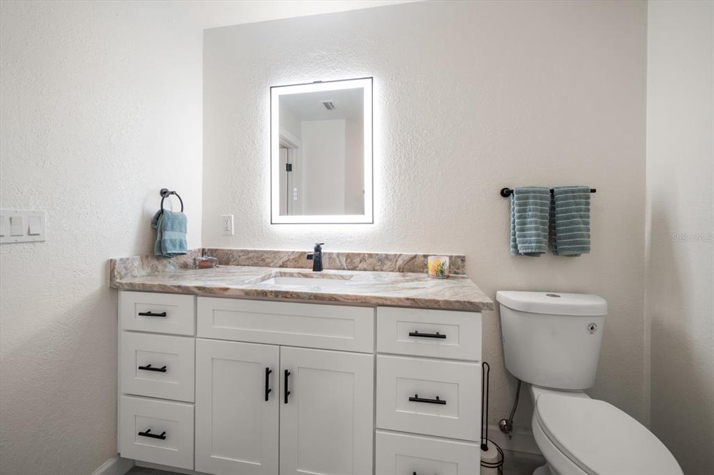 2505 Bay Boulevard, Unit 4 Indian Rocks Beach, FL 33785 - Photo 21 of 63 a bathroom with a granite countertop toilet sink and mirror