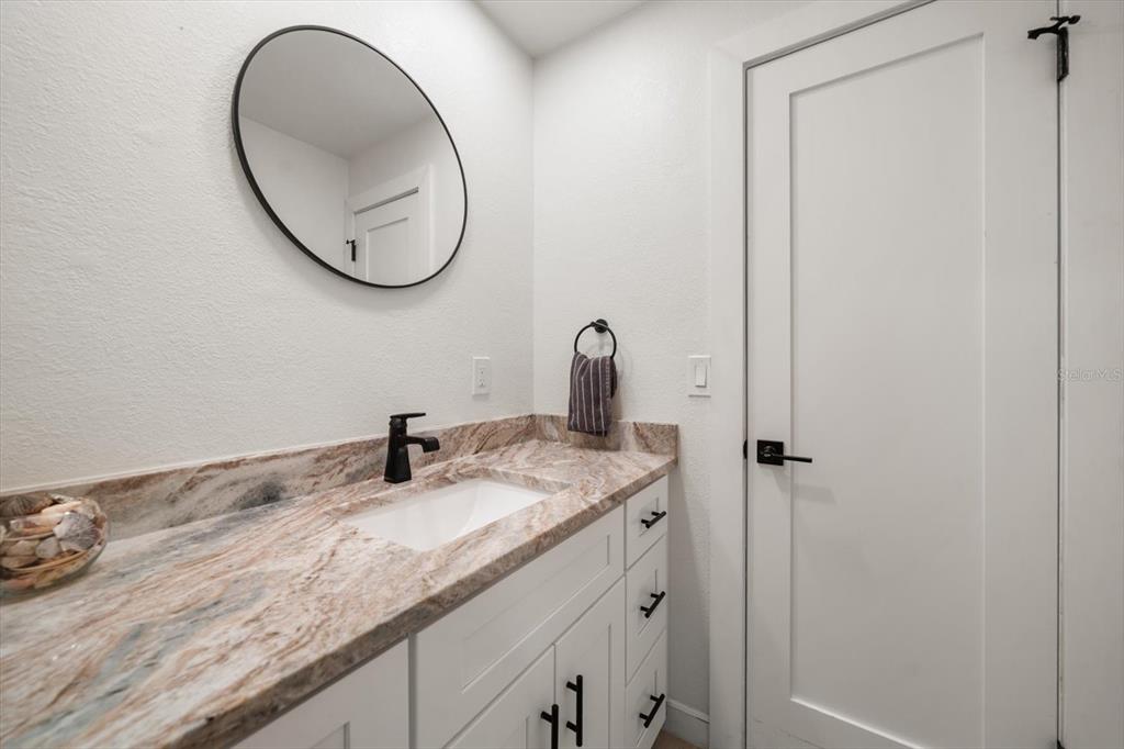 2505 Bay Boulevard, Unit 4 Indian Rocks Beach, FL 33785 - Photo 28 of 63 a bathroom with a granite countertop sink and a mirror