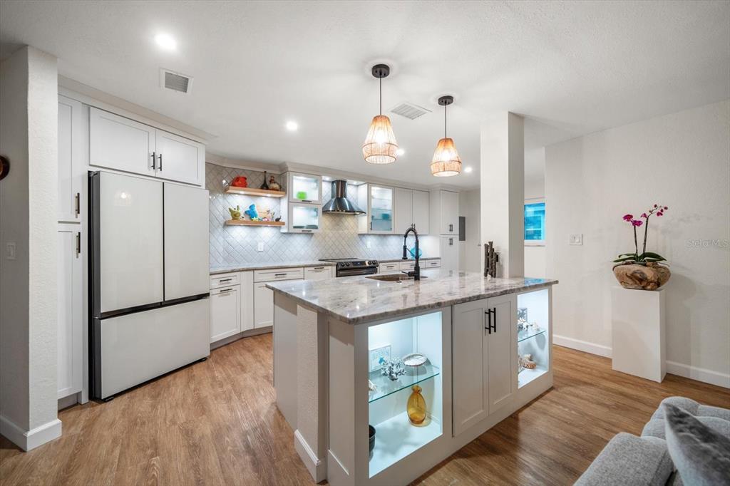 2505 Bay Boulevard, Unit 4 Indian Rocks Beach, FL 33785 - Photo 4 of 63 a kitchen with granite countertop a white refrigerator a sink dishwasher a oven and a dining table with wooden floor