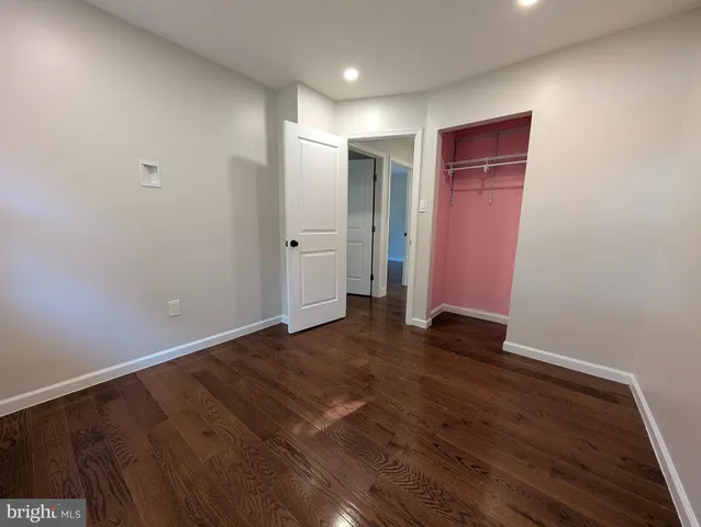 a view of an empty room with wooden floor and closet