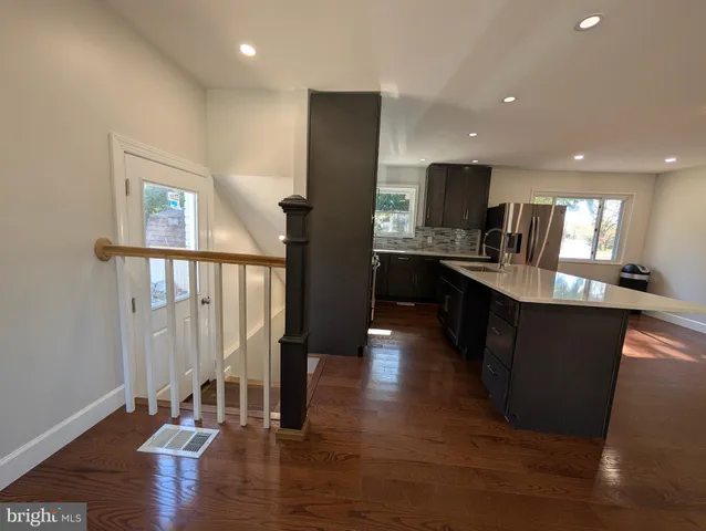 a kitchen with stainless steel appliances granite countertop a refrigerator a sink dishwasher a stove and white cabinets with wooden floor