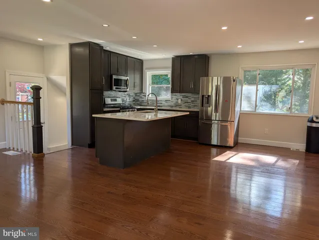 a kitchen with stainless steel appliances granite countertop a refrigerator and a stove top oven with wooden floor