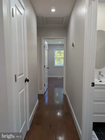 a view of a hallway with wooden floor and a living room
