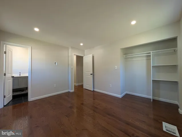 a view of an empty room with wooden floor and closet