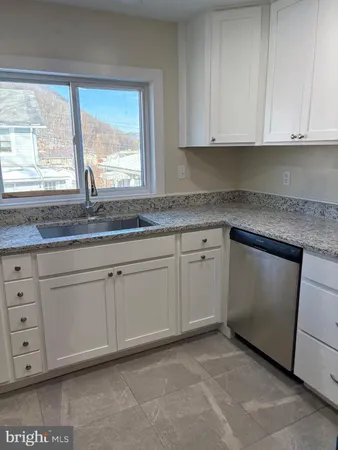 a kitchen with granite countertop white cabinets and a sink