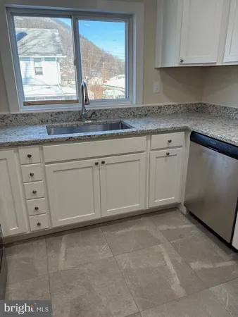 a kitchen with granite countertop white cabinets and window