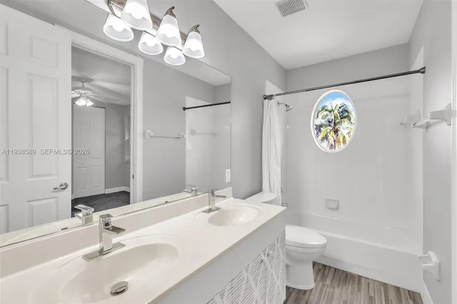 a bathroom with a sink a toilet a large mirror and shower