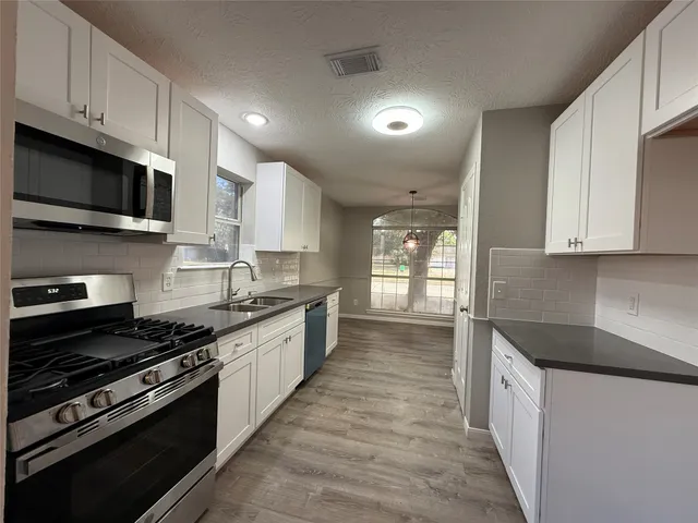 a large kitchen with stainless steel appliances granite countertop a stove and a sink