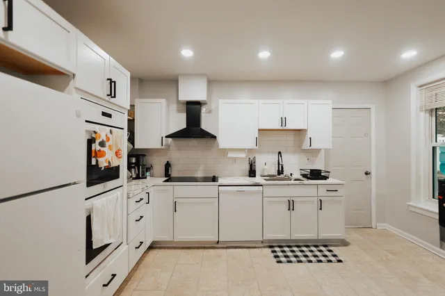 a kitchen with stainless steel appliances a sink a stove a refrigerator cabinets and a window