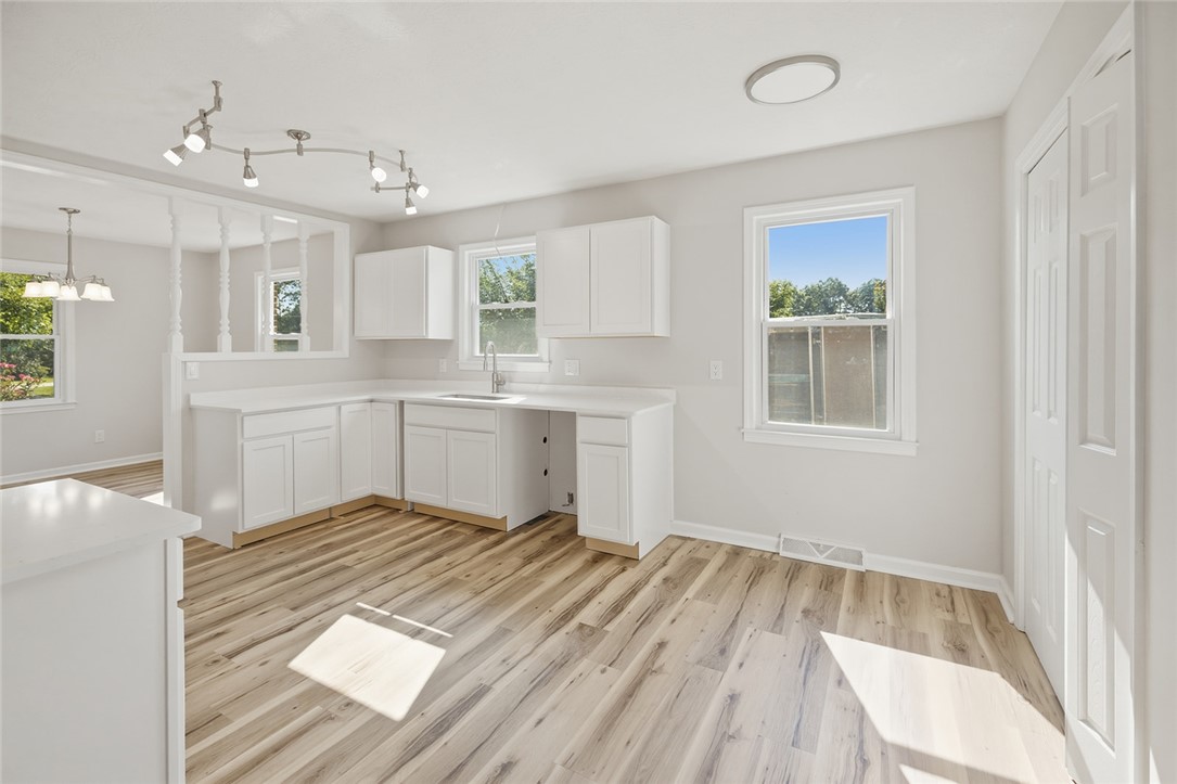 902 Cherokee Road Pelzer, SC 29669 - Photo 24 of 38 A well-lit kitchen with sleek white cabinetry and durable wood flooring.