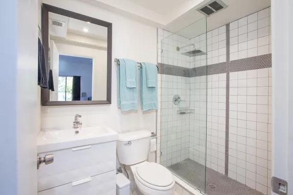 a bathroom with a shower sink vanity mirror and toilet