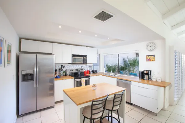 a kitchen with sink a refrigerator and chairs