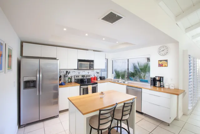 a kitchen with sink a refrigerator and chairs