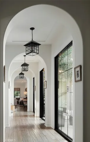 a view of a livingroom with a chandelier fireplace wooden floor and windows