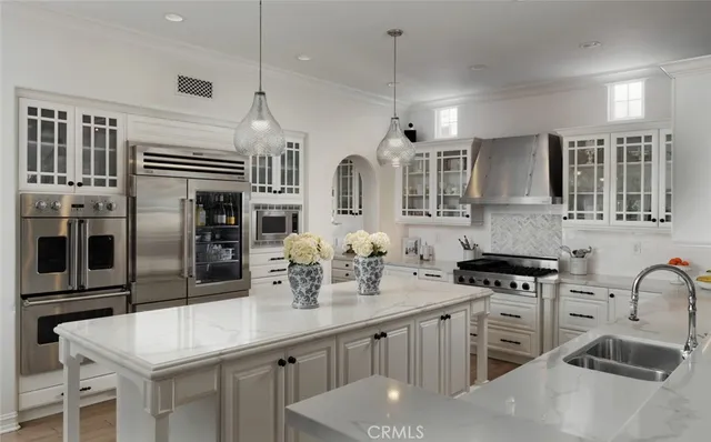 a kitchen with stainless steel appliances granite countertop a sink a stove a refrigerator cabinets and chairs