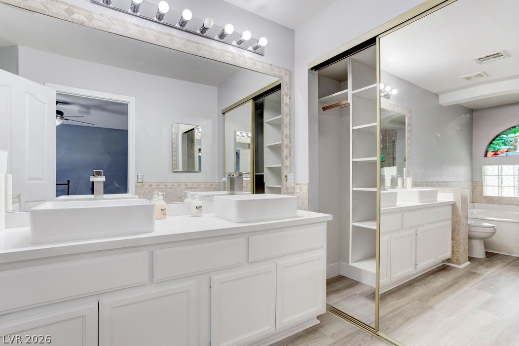 1 Rising Sun Court Henderson, NV 89074 - Photo 34 of 47 Dual vessel sinks and mirrored closets enhance this primary bathroom's spacious and functional design.