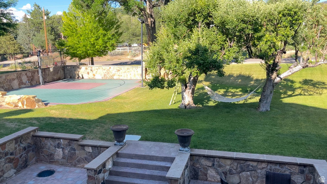 426 West Center Street Parowan, UT 84761 - Photo 77 of 107 Expansive backyard featuring a multi-sport court with basketball hoops, a manicured lawn, and mature trees