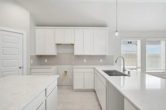 a kitchen with a sink dishwasher a stove top oven a refrigerator and white cabinets with wooden floor