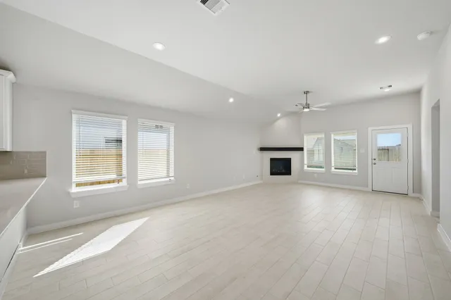an empty room with windows and fireplace