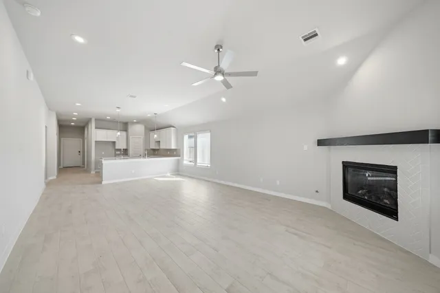 an empty room with a fireplace and a ceiling fan