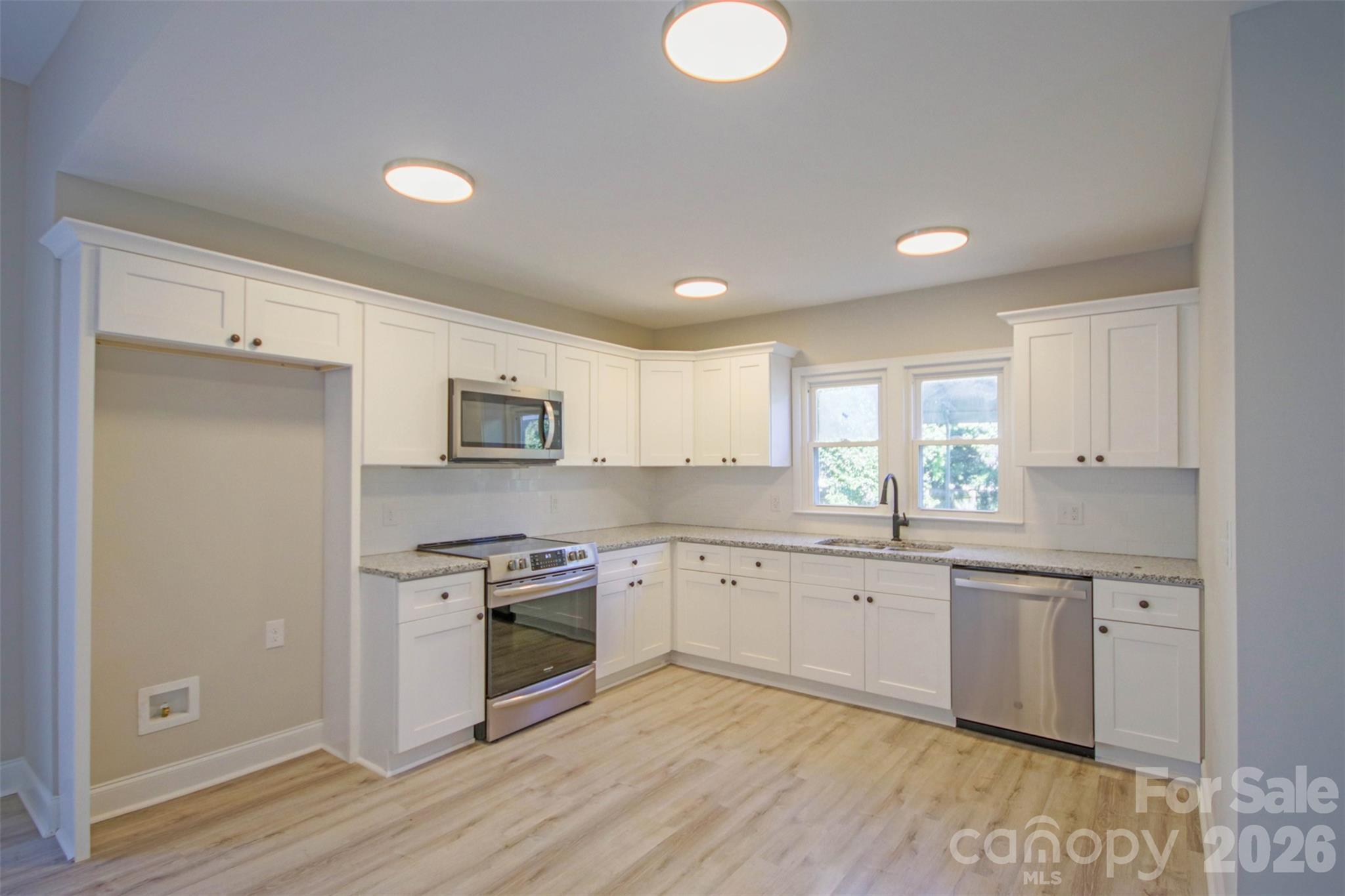 119 Marion Street Clover, SC 29710 - Photo 30 of 46 a kitchen with stainless steel appliances granite countertop a stove top oven a sink and white cabinets with wooden floor