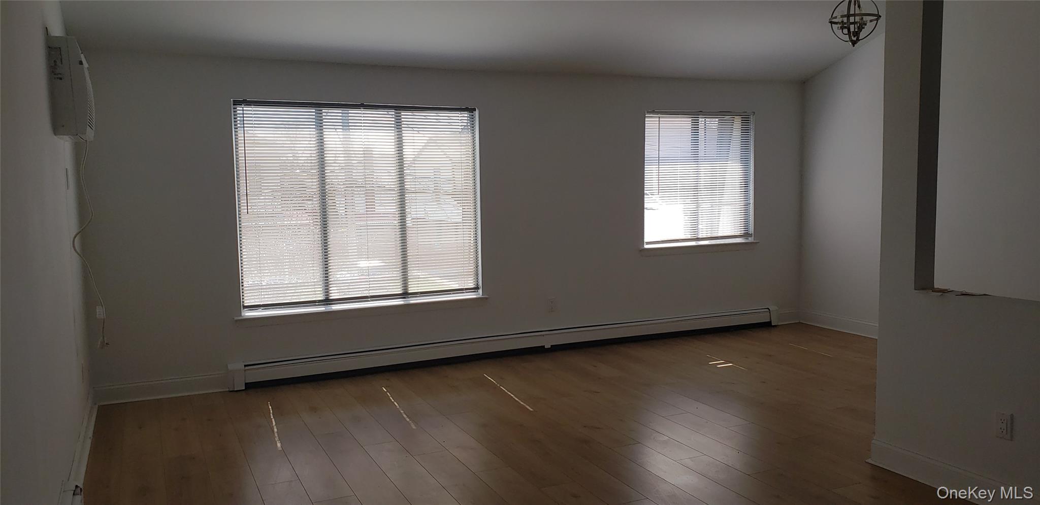 184-11 144th Road Queens, NY 11413 - Photo 13 of 16 an empty room with wooden floor and windows