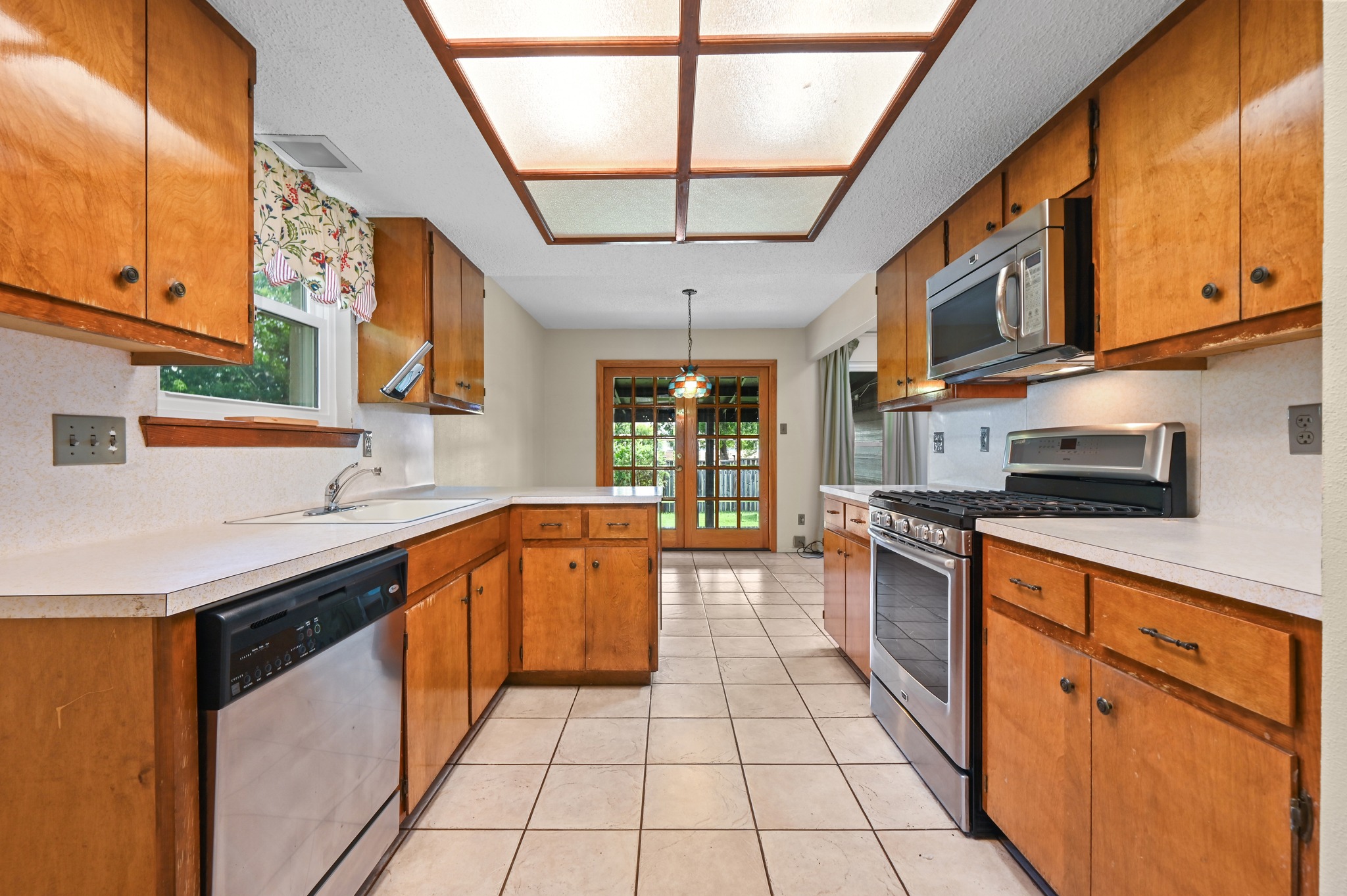 10504 Hard Rock Road Austin, TX 78750 - Photo 13 of 28 A well-equipped kitchen features tile flooring and ample cabinetry, with direct backyard access through elegant French doors.