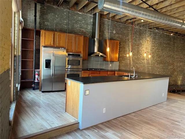 a kitchen with stainless steel appliances granite countertop a sink a stove and wooden floor