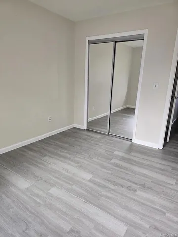 an empty room with wooden floor and mirror