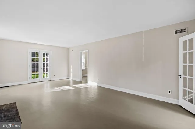 an empty room with windows fireplace and wooden floor