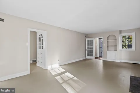 an empty room with windows and fireplace