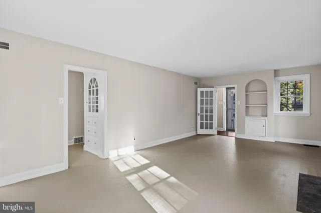 an empty room with windows and fireplace