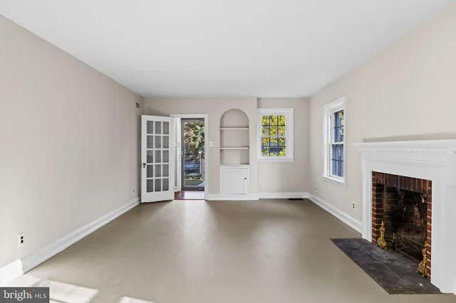 an empty room with windows and fireplace