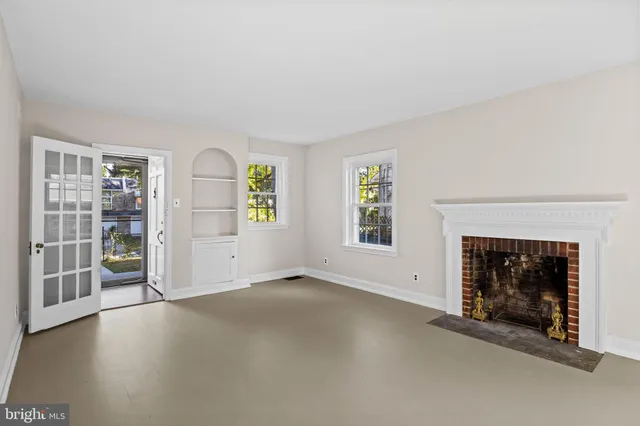 a view of an empty room with a fireplace and window