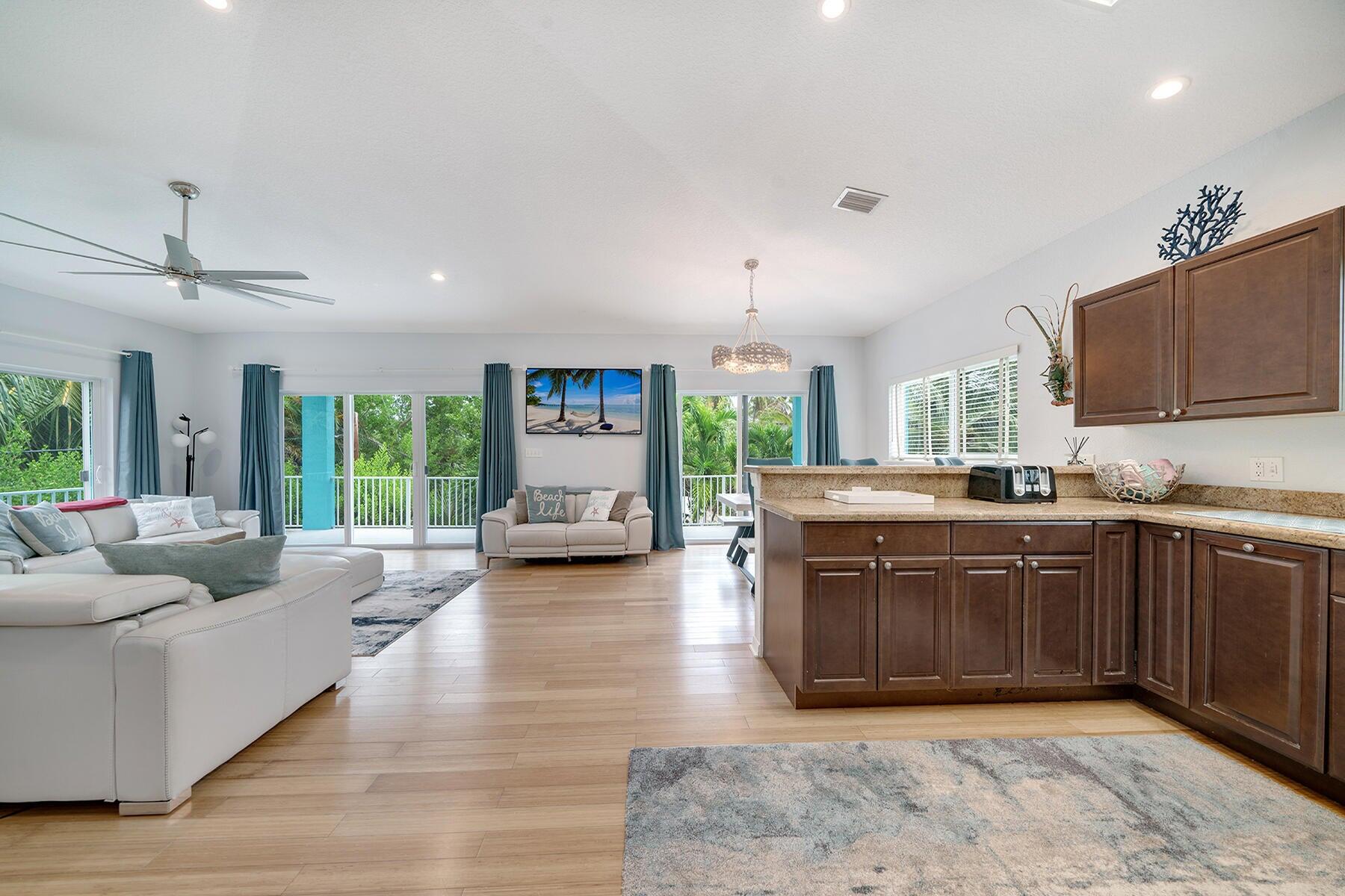 191 Carroll Street Islamorada, FL 33036 - Photo 21 of 40 a kitchen with stainless steel appliances granite countertop a stove top oven a sink dishwasher a dining table and chairs with wooden floor