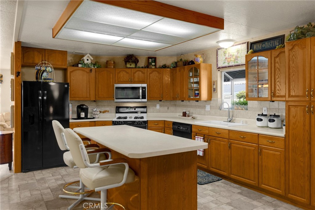10210 Base Line Road, Unit 235 Rancho Cucamonga, CA 91701 - Photo 15 of 33 a kitchen with stainless steel appliances a sink a stove a refrigerator cabinets and a dining table with chairs