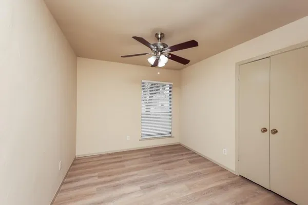 an empty room with a window and a fan