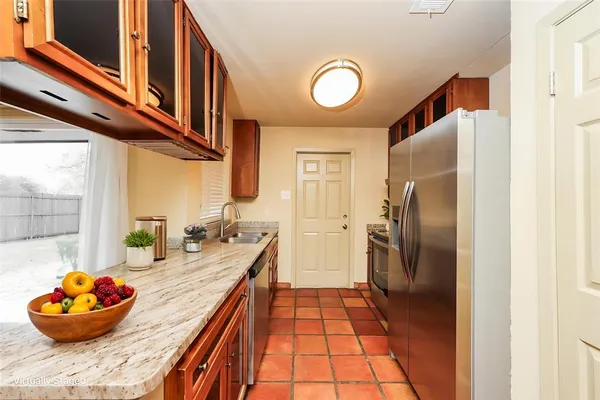 a kitchen with stainless steel appliances granite countertop a sink and a refrigerator