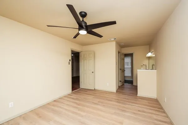 a view of empty room with wooden floor and fan