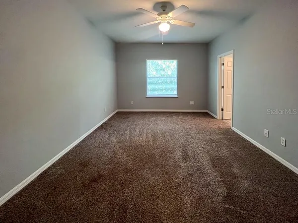 an empty room with windows and chandelier fan