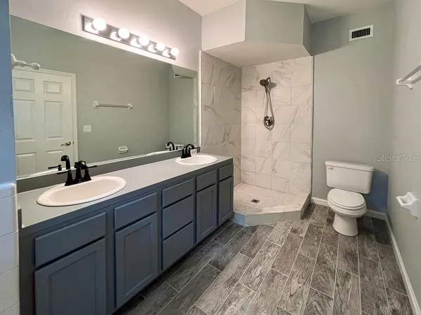a spacious bathroom with a double vanity sink toilet and shower