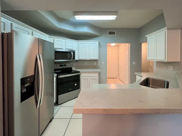 a kitchen with granite countertop a refrigerator a sink a stove a microwave a counter space and cabinets