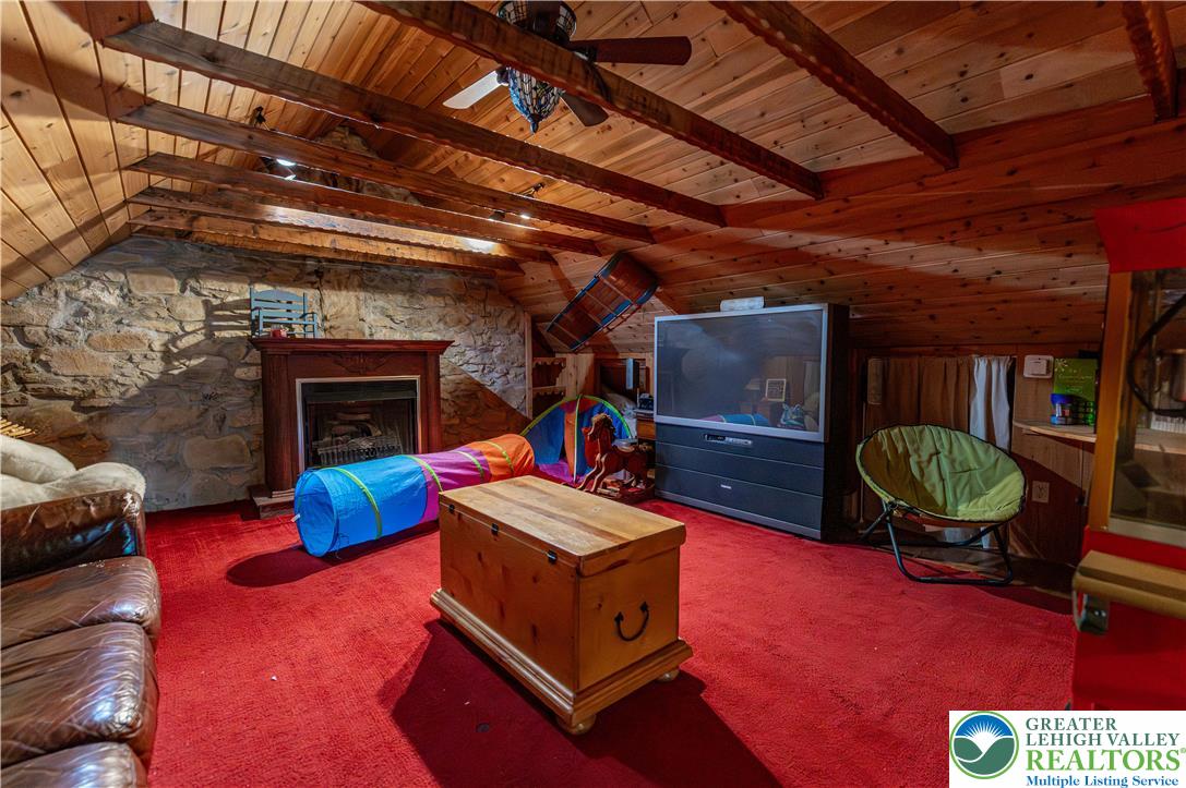 2485 Hieter Road Quakertown, PA 18951 - Photo 49 of 97 A cozy attic space boasts exposed wooden beams and a charming stone accent wall with a fireplace.