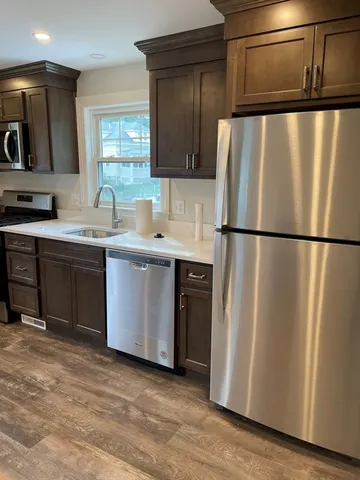 a kitchen with stainless steel appliances granite countertop a sink a stove a refrigerator cabinets and a window