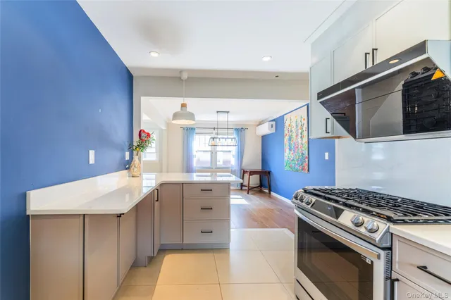 a view of an empty room with wooden floor and a kitchen