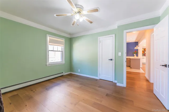 a view of empty room with wooden floor and fan