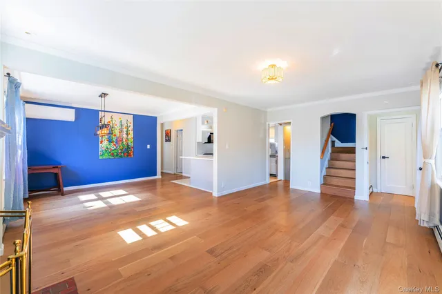 a view of an empty room with wooden floor and stairs