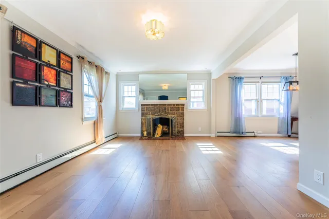 an empty room with wooden floor fireplace and windows