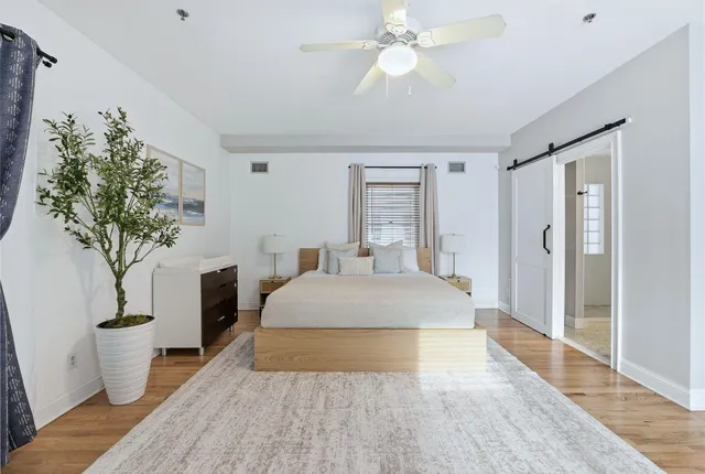 a spacious bedroom with a large bed a chandelier and closet