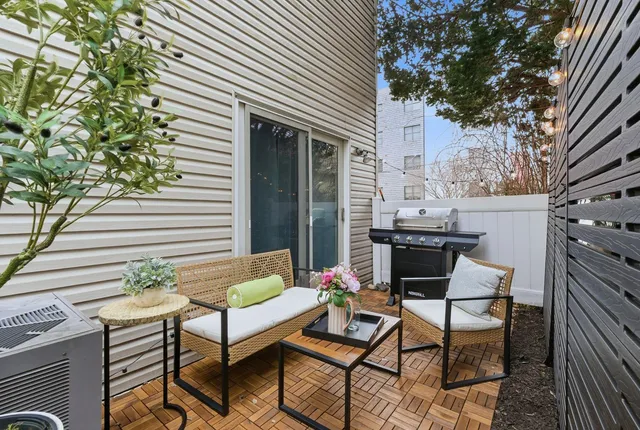 a patio with table and chairs and potted plants